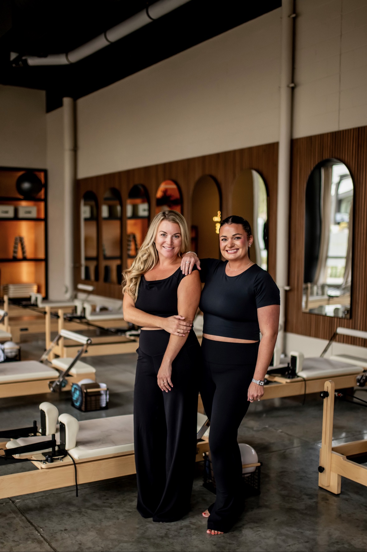 Two PureForm clients standing together among the Reformers inside the Sioux City studio